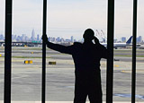 Man speaking on cell phone, while viewing the runway through the waiting area window